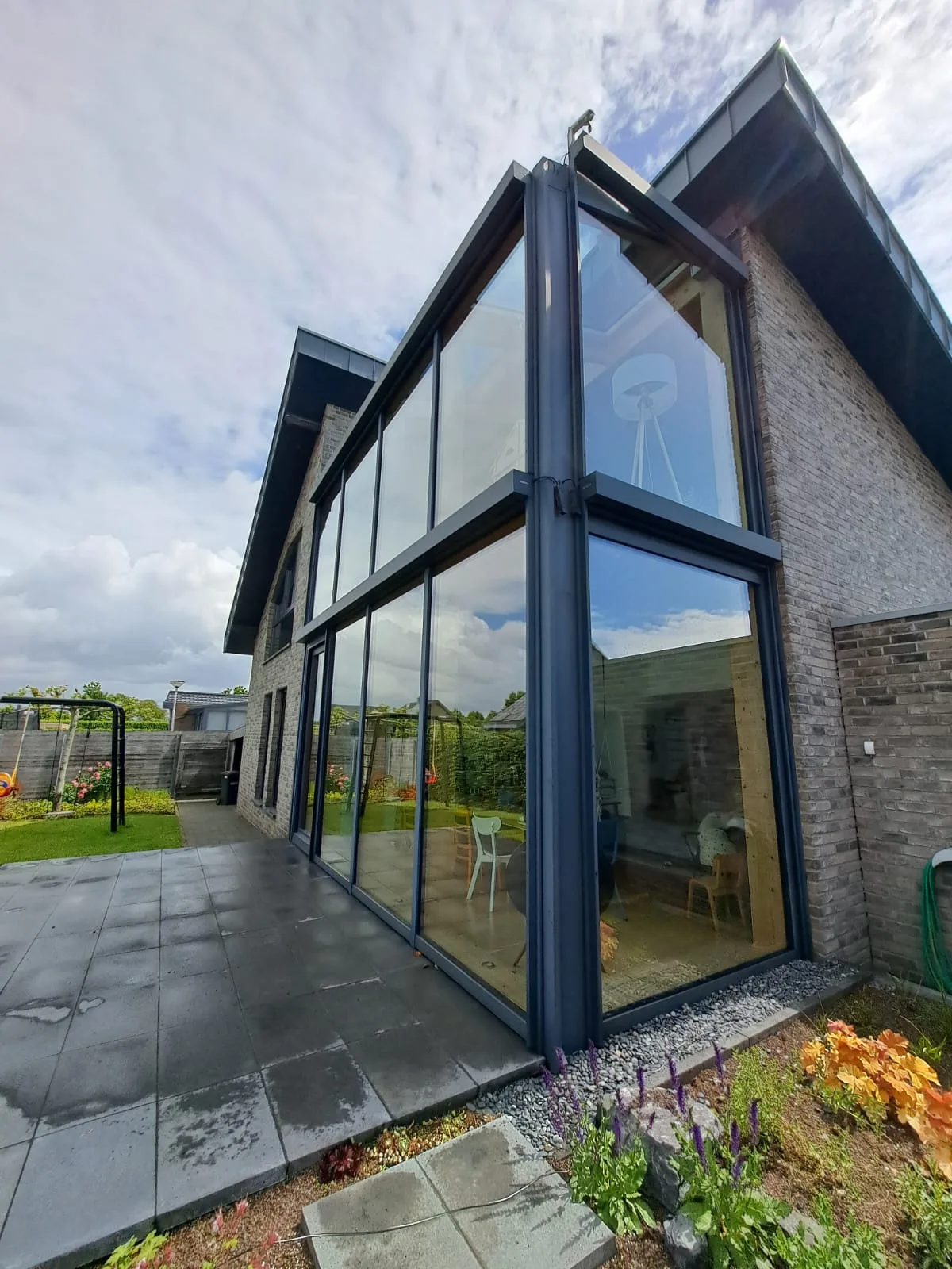 Gereinigter zweigeschossiger Glasgiebel an einem Einfamilienhaus mit Terrasse